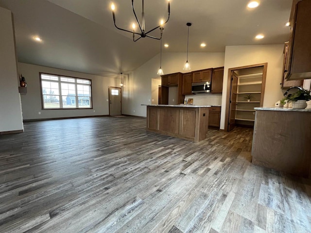 kitchen with pendant lighting, lofted ceiling, a kitchen island, decorative backsplash, and dark hardwood / wood-style floors