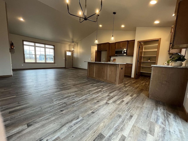 kitchen with tasteful backsplash, decorative light fixtures, a kitchen island, an inviting chandelier, and dark wood-type flooring