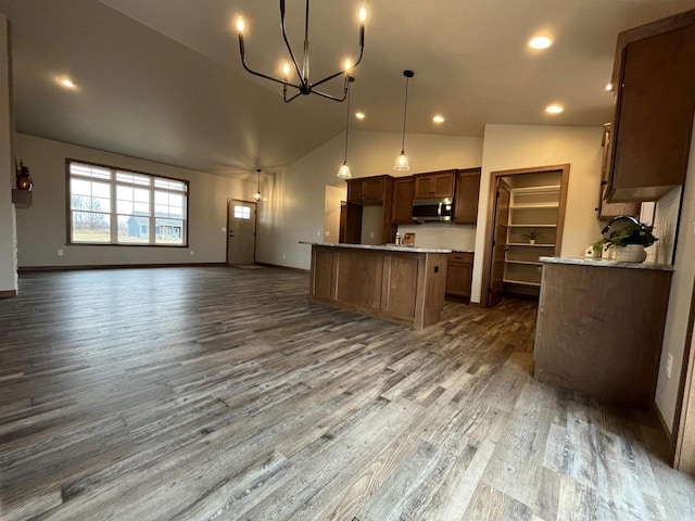 kitchen with pendant lighting, a kitchen island, dark wood-type flooring, decorative backsplash, and vaulted ceiling