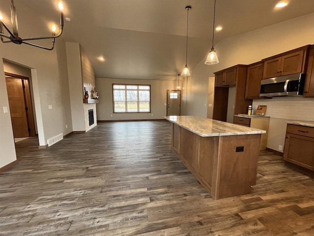 kitchen featuring light stone countertops, decorative backsplash, a large fireplace, high vaulted ceiling, and pendant lighting