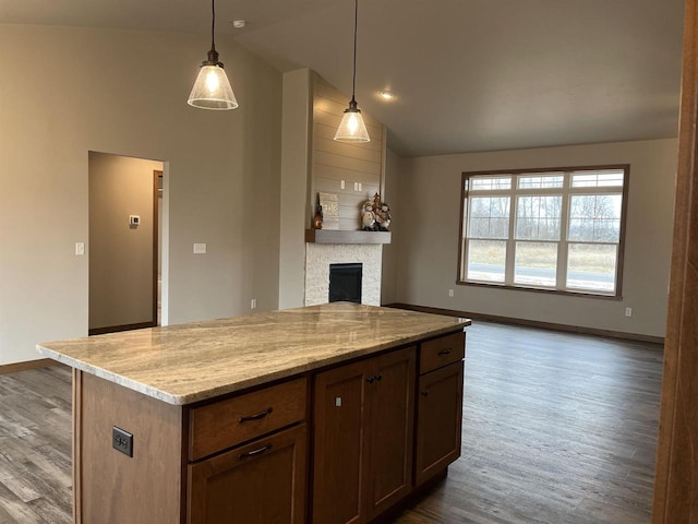 kitchen with hanging light fixtures, light stone counters, a fireplace, dark hardwood / wood-style floors, and lofted ceiling