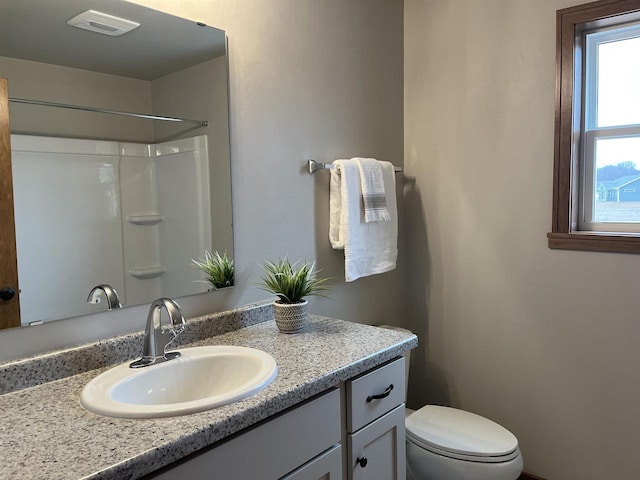 bathroom featuring vanity, toilet, and a shower