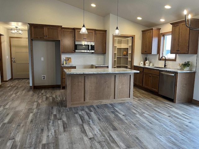 kitchen with pendant lighting, sink, a kitchen island, lofted ceiling, and stainless steel appliances