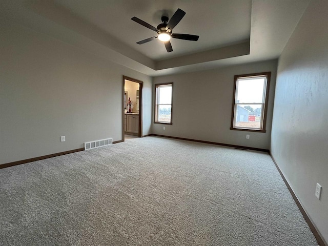 carpeted spare room with ceiling fan and a raised ceiling