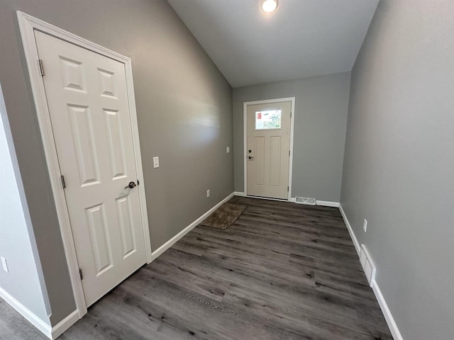 doorway to outside with baseboards, visible vents, vaulted ceiling, and dark wood-type flooring