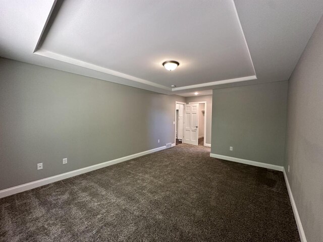 carpeted empty room with a tray ceiling