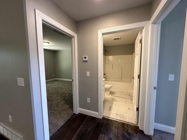 bathroom with hardwood / wood-style flooring, toilet, and tub / shower combination