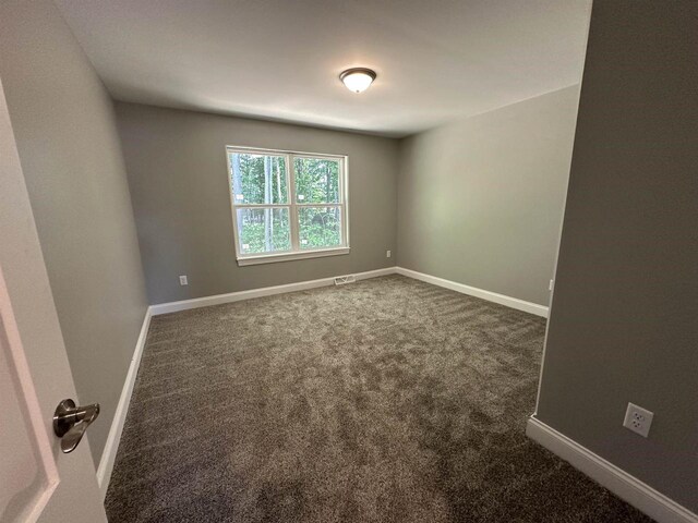 spare room with dark carpet