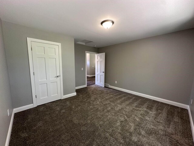 unfurnished bedroom with dark colored carpet and a closet