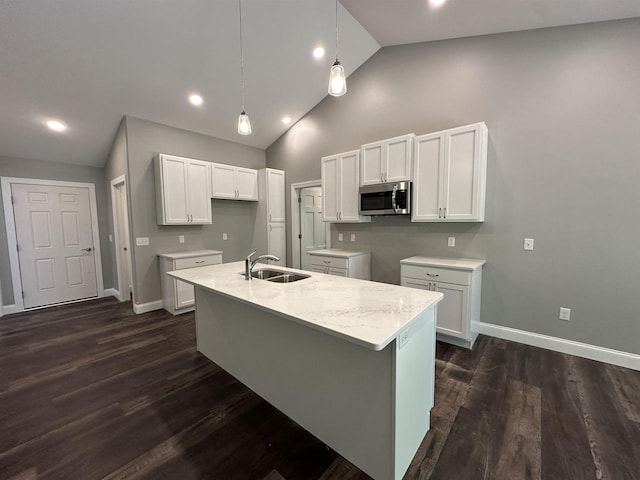 kitchen with high vaulted ceiling, white cabinetry, a kitchen island with sink, and sink