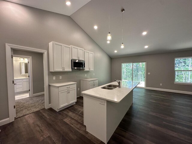 kitchen featuring sink, dark hardwood / wood-style floors, decorative light fixtures, a kitchen island with sink, and white cabinets