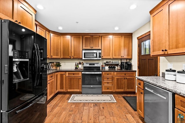 kitchen featuring dark stone countertops, hardwood / wood-style flooring, and stainless steel appliances