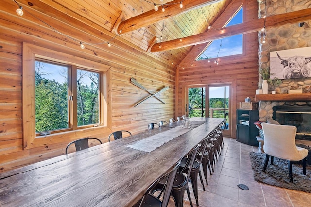 tiled dining area featuring wood ceiling, beamed ceiling, wood walls, a fireplace, and high vaulted ceiling