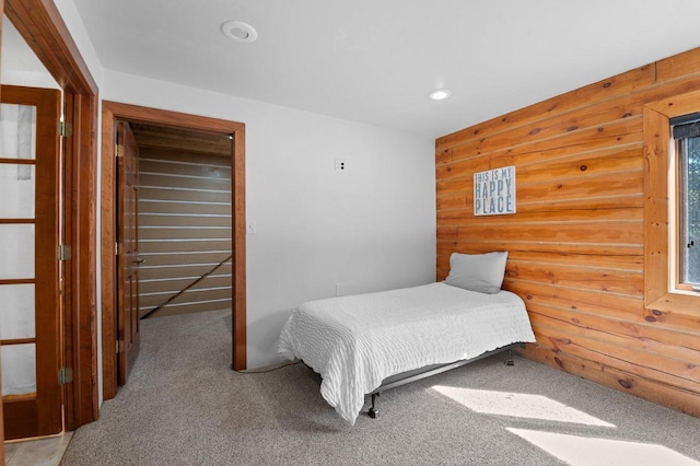 bedroom with wooden walls and carpet flooring