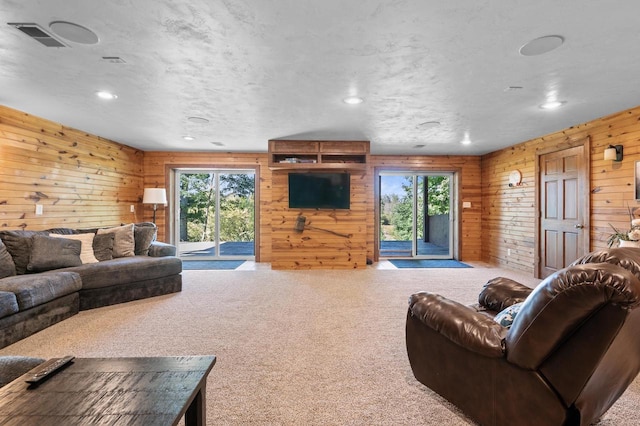 living room featuring wooden walls, plenty of natural light, and carpet floors