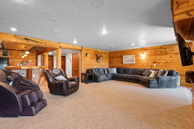 living room with bar area, light colored carpet, and wooden walls