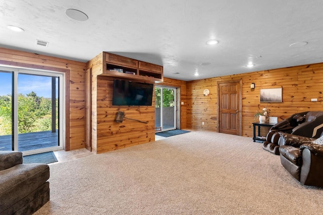 living room with carpet floors, wood walls, and a healthy amount of sunlight