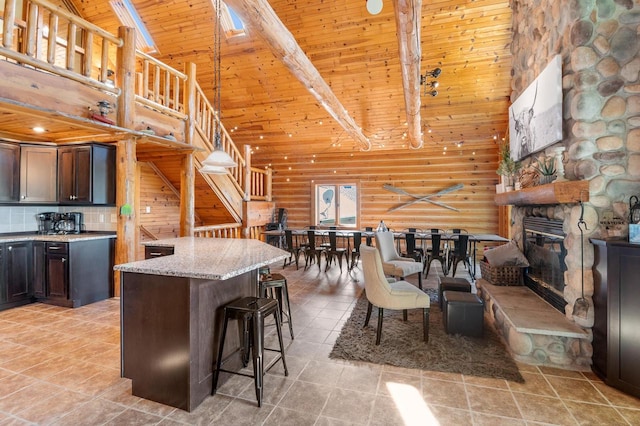 kitchen with wood ceiling, beamed ceiling, high vaulted ceiling, a kitchen breakfast bar, and a stone fireplace