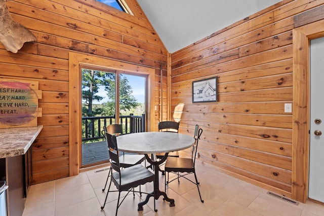 tiled dining area with lofted ceiling and wood walls