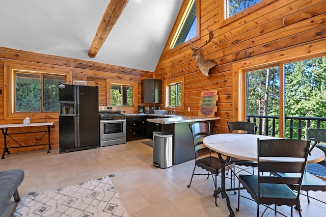 kitchen featuring a healthy amount of sunlight, black fridge with ice dispenser, wooden walls, and stainless steel range with gas stovetop