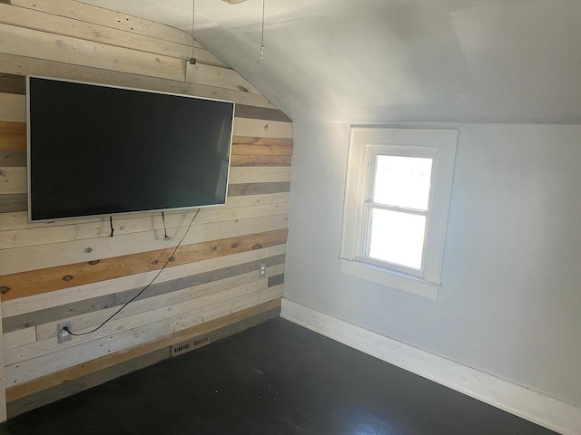 additional living space featuring wooden walls and lofted ceiling