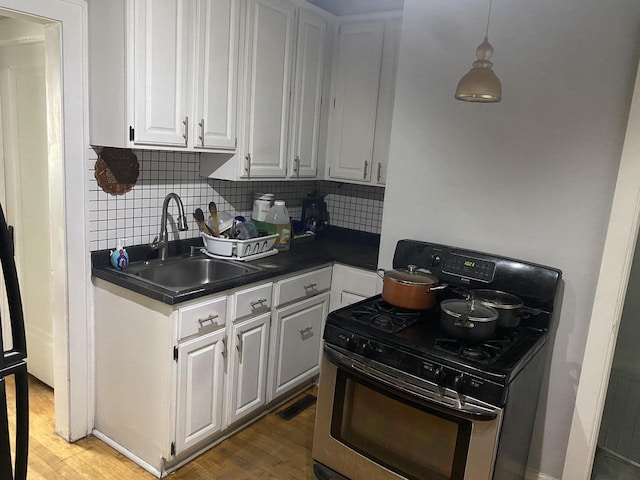 kitchen with white cabinets, sink, gas range, backsplash, and hardwood / wood-style floors