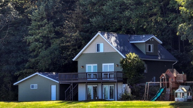 back of house with a playground, a wooden deck, and a yard