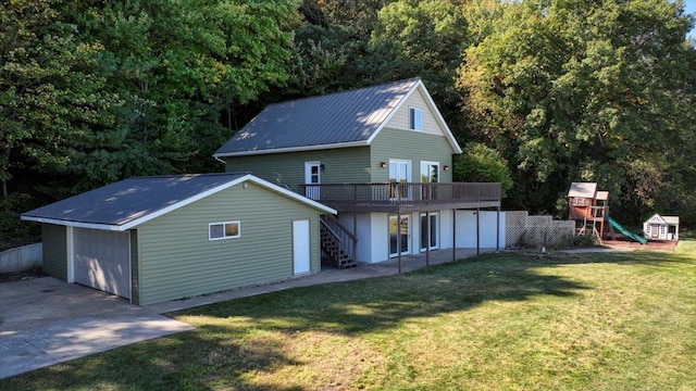 rear view of property featuring a playground, a yard, and a wooden deck