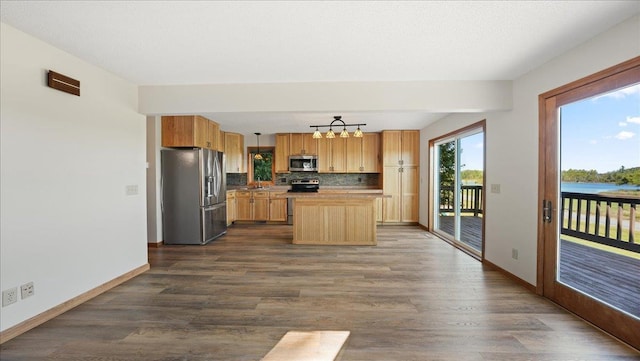 kitchen with dark wood-type flooring, tasteful backsplash, hanging light fixtures, a kitchen island, and stainless steel appliances