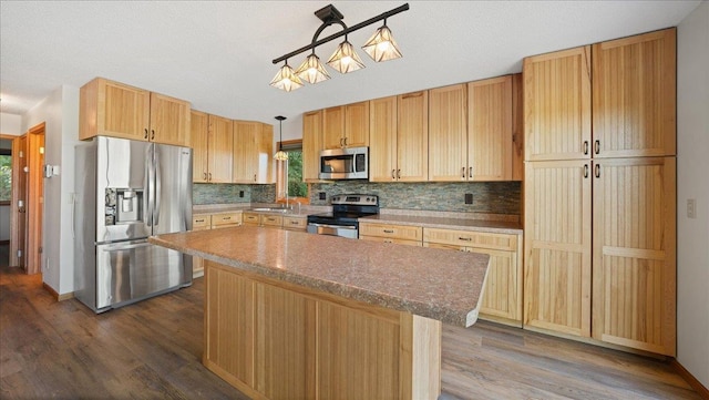 kitchen with a center island, dark wood-type flooring, sink, stainless steel appliances, and decorative light fixtures