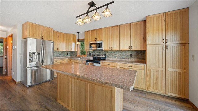 W9037 Ridgeview Trl, New Lisbon, WI 53950 - kitchen featuring stainless steel appliances, dark wood-type flooring, decorative backsplash, a center island, and a sink