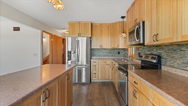 kitchen featuring sink, a textured ceiling, decorative light fixtures, appliances with stainless steel finishes, and dark hardwood / wood-style flooring