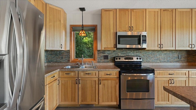 kitchen with pendant lighting, sink, a textured ceiling, backsplash, and appliances with stainless steel finishes