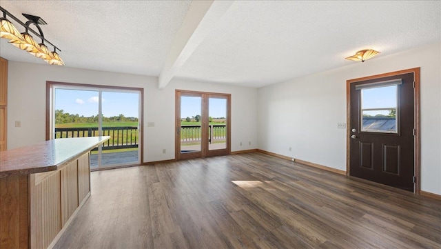 unfurnished living room featuring french doors, a textured ceiling, plenty of natural light, and dark hardwood / wood-style flooring