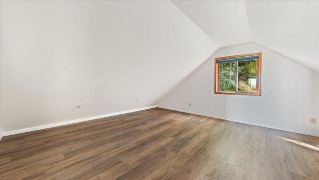 additional living space featuring vaulted ceiling and dark wood-type flooring