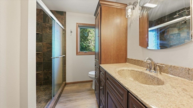 bathroom with wood-type flooring, vanity, toilet, and an enclosed shower