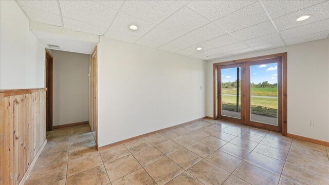 W9037 Ridgeview Trl, New Lisbon, WI 53950 - empty room featuring a drop ceiling, french doors, baseboards, recessed lighting, and light tile patterned flooring