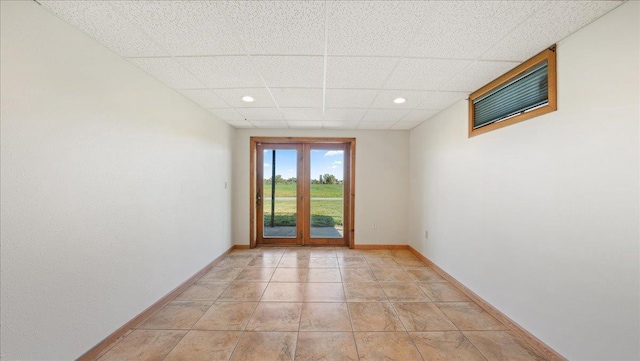 tiled empty room with french doors and a paneled ceiling