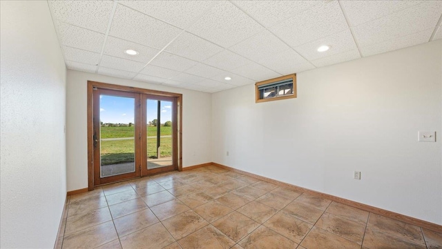 spare room featuring a paneled ceiling and light tile patterned floors