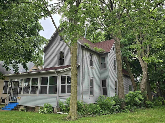 view of side of home with a sunroom and a lawn