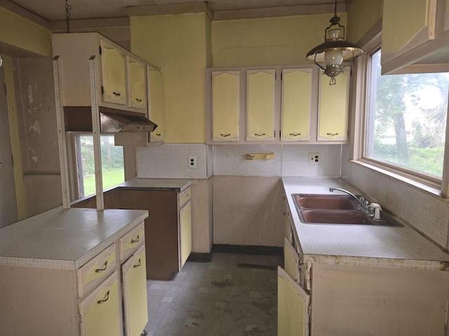 kitchen featuring a notable chandelier, backsplash, decorative light fixtures, and sink