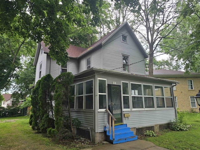 view of front of house with a front yard and a sunroom