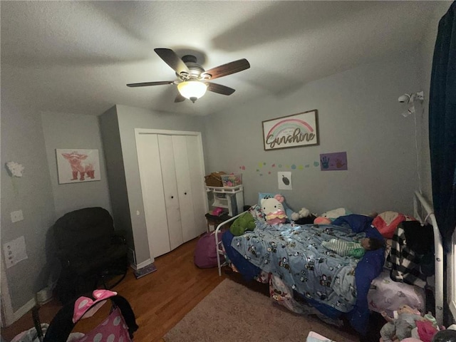 bedroom with ceiling fan, a closet, and wood-type flooring