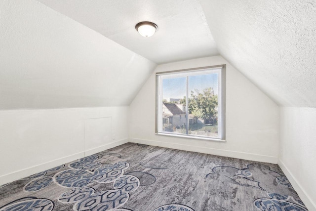 bonus room featuring vaulted ceiling, carpet flooring, and a textured ceiling