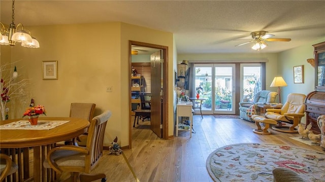 dining area featuring ceiling fan with notable chandelier and light wood-type flooring