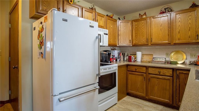 kitchen with decorative backsplash, white appliances, and a textured ceiling