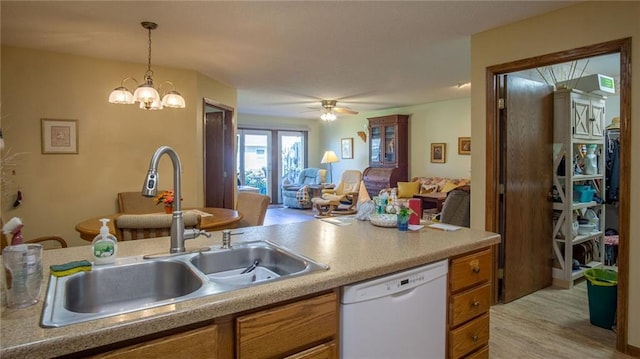 kitchen with light wood-type flooring, pendant lighting, ceiling fan with notable chandelier, sink, and white dishwasher