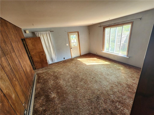 carpeted empty room featuring plenty of natural light and wood walls