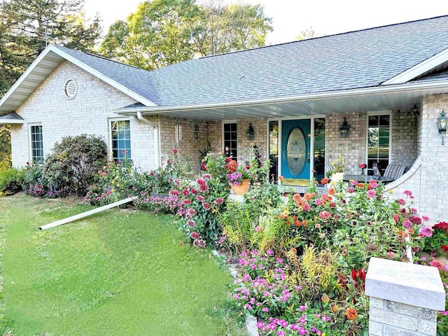 63574 Lohmann Ln, Eastman, WI 52626 - ranch-style home with roof with shingles, covered porch, brick siding, and a front lawn