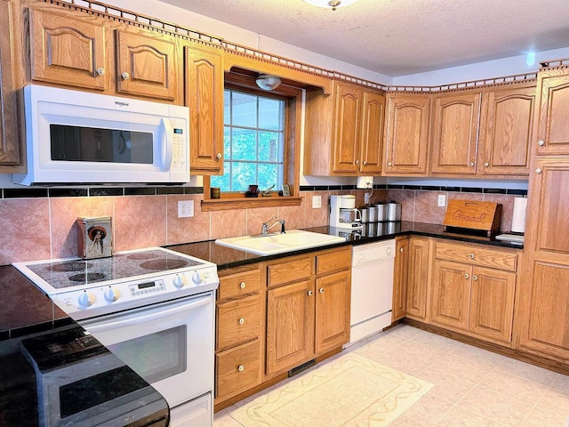 63574 Lohmann Ln, Eastman, WI 52626 - kitchen featuring white appliances, a sink, brown cabinets, backsplash, and dark countertops